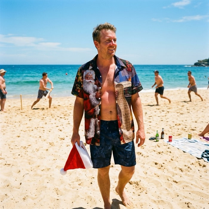 Man in an open festive shirt over board shorts on the beach on Christmas Day