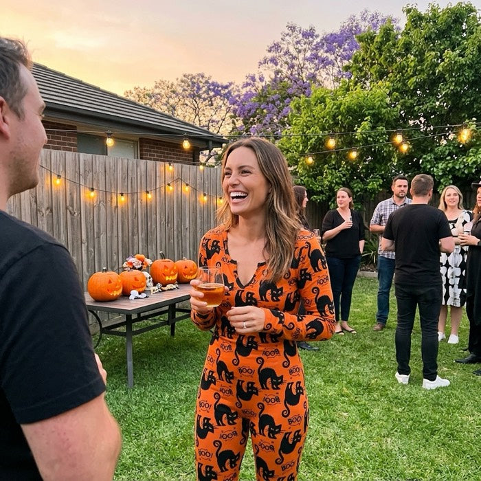 Woman in a black cat print Halloween jumpsuit at a backyard party