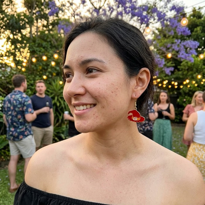 Close portrait of a woman wearing pumpkin Halloween earrings at dusk